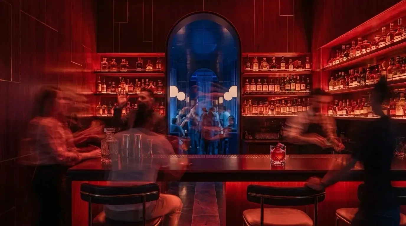 Mujize's crimson bar glows beside the cobalt room as bartenders work behind the counter.
